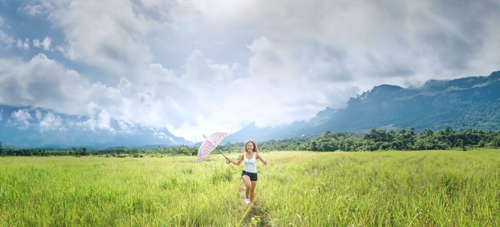 Asian women travel relax in the holiday. Running umbrella sunshine on a green pasture. Stock Free