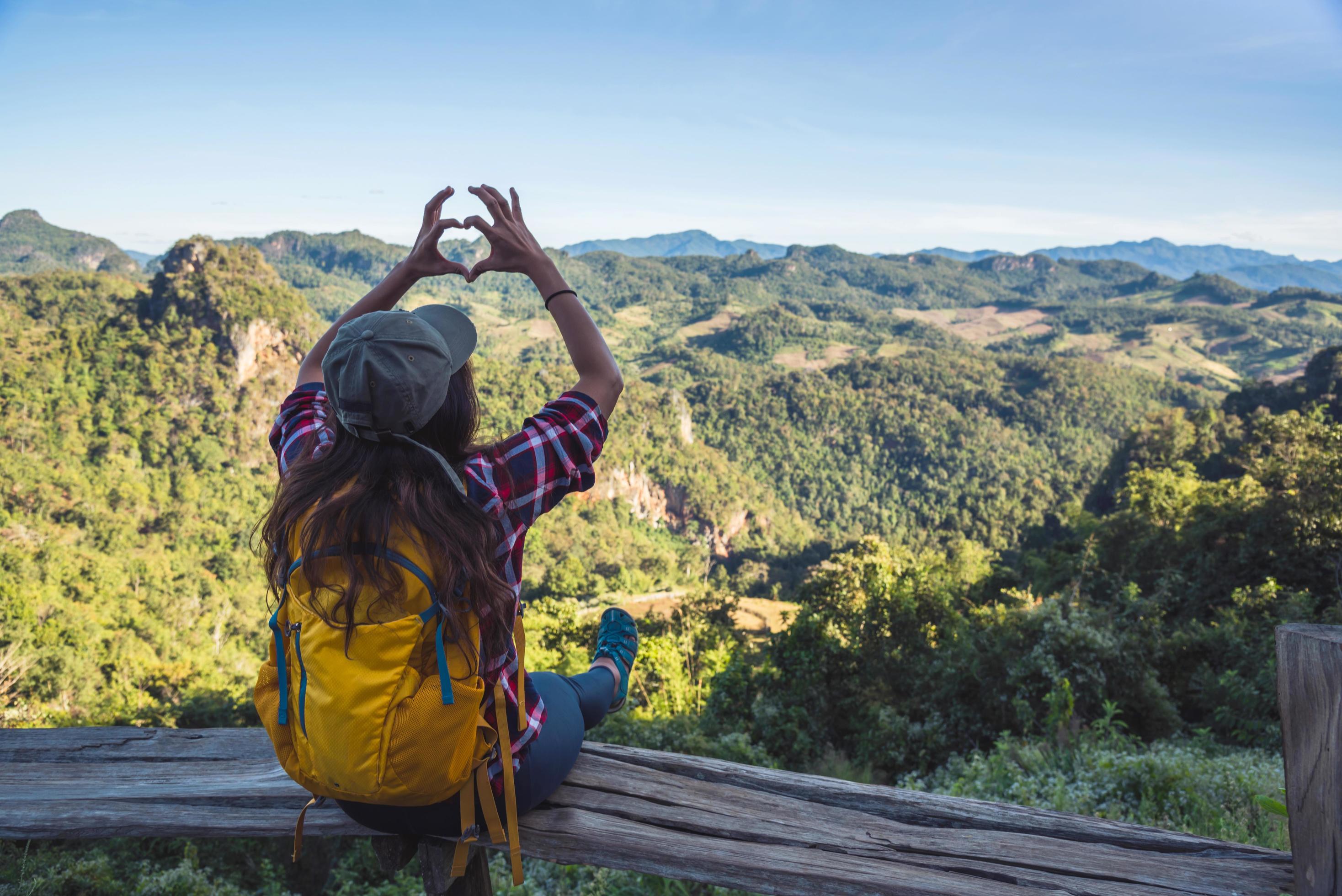 Young woman Tourists with backpacks Happy to travel She raised her hand to make a heart shape and enjoy the natural scenery on the mountain. Stock Free