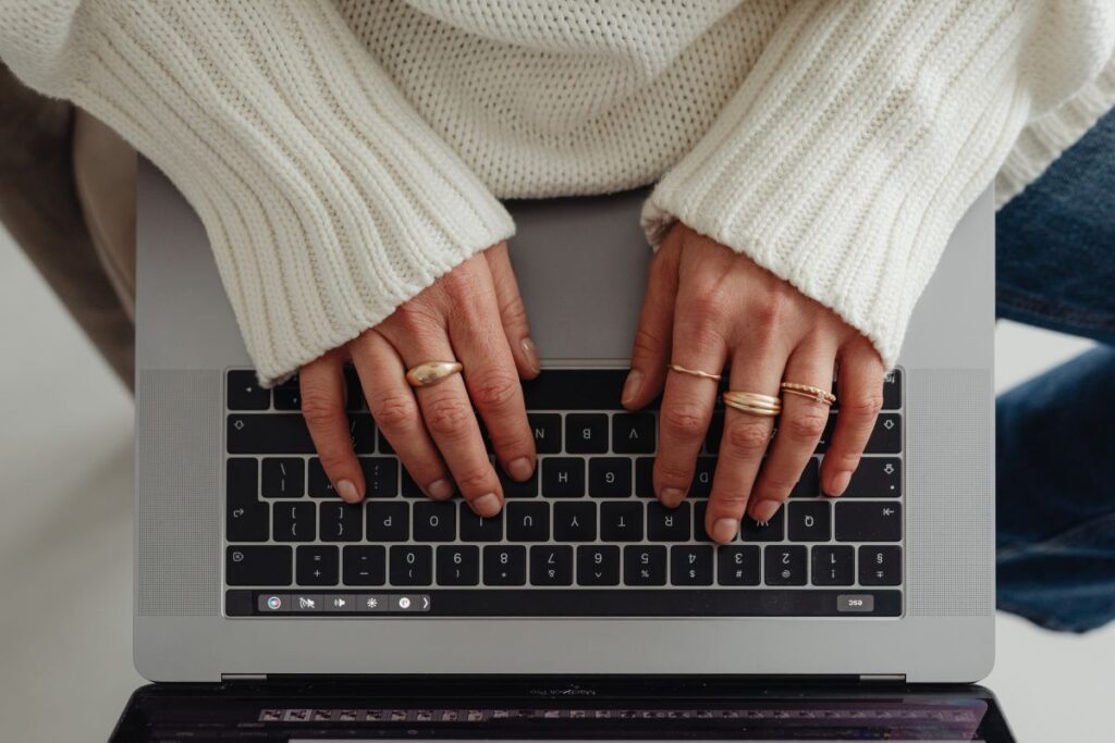 Woman in a white sweater – jewelry – laptop work – fashion Stock Free