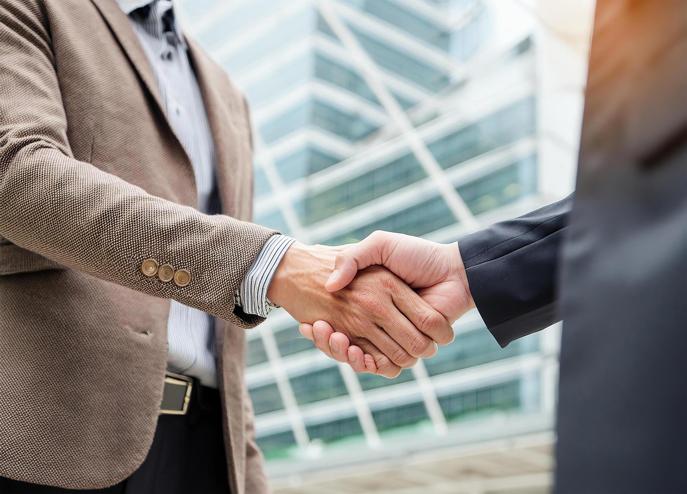 Close up of hand of Two business people shaking hands,blurred building background Stock Free