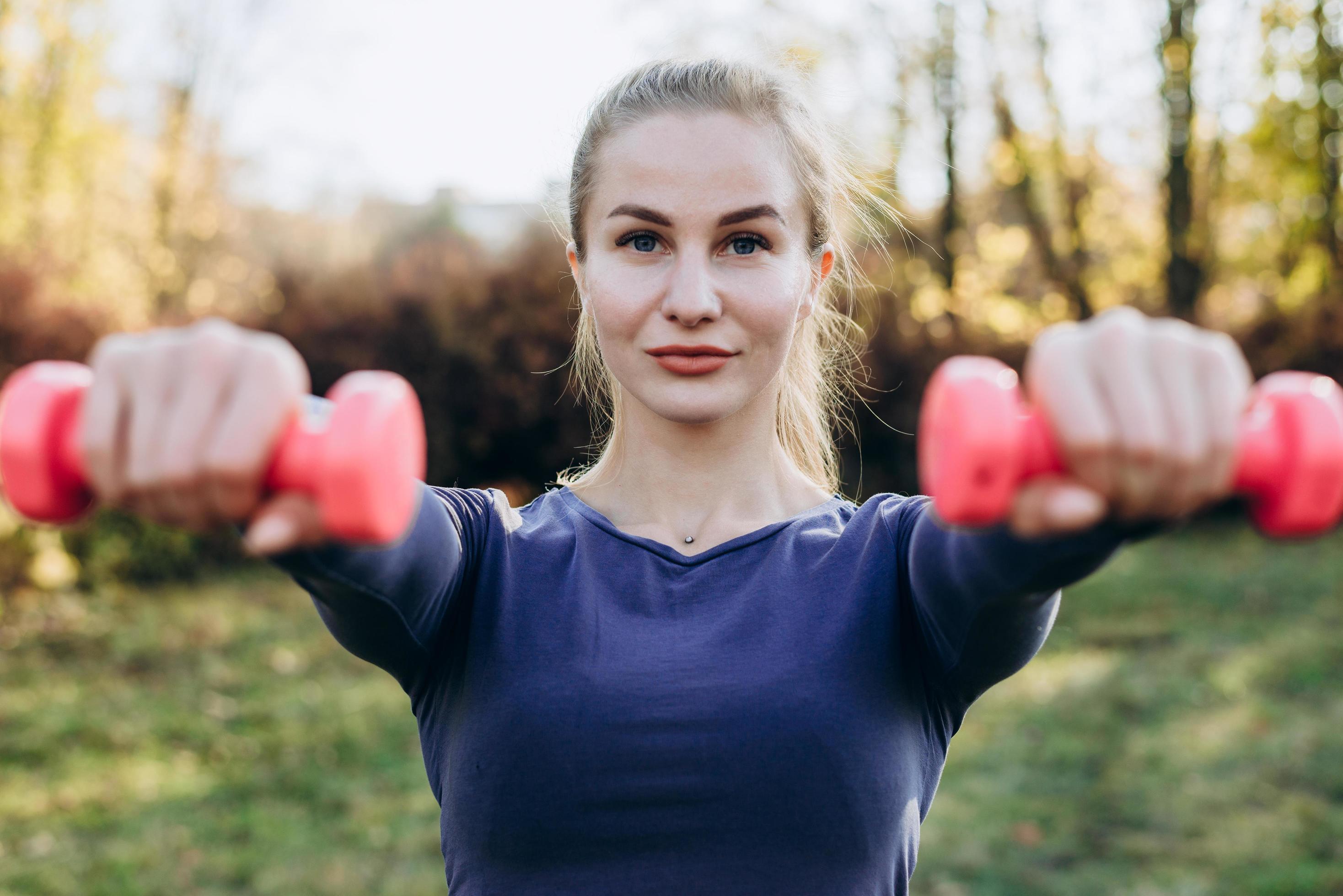 Beautiful young woman working exercise with dumbbells, as a part of her lifestyle. Stock Free