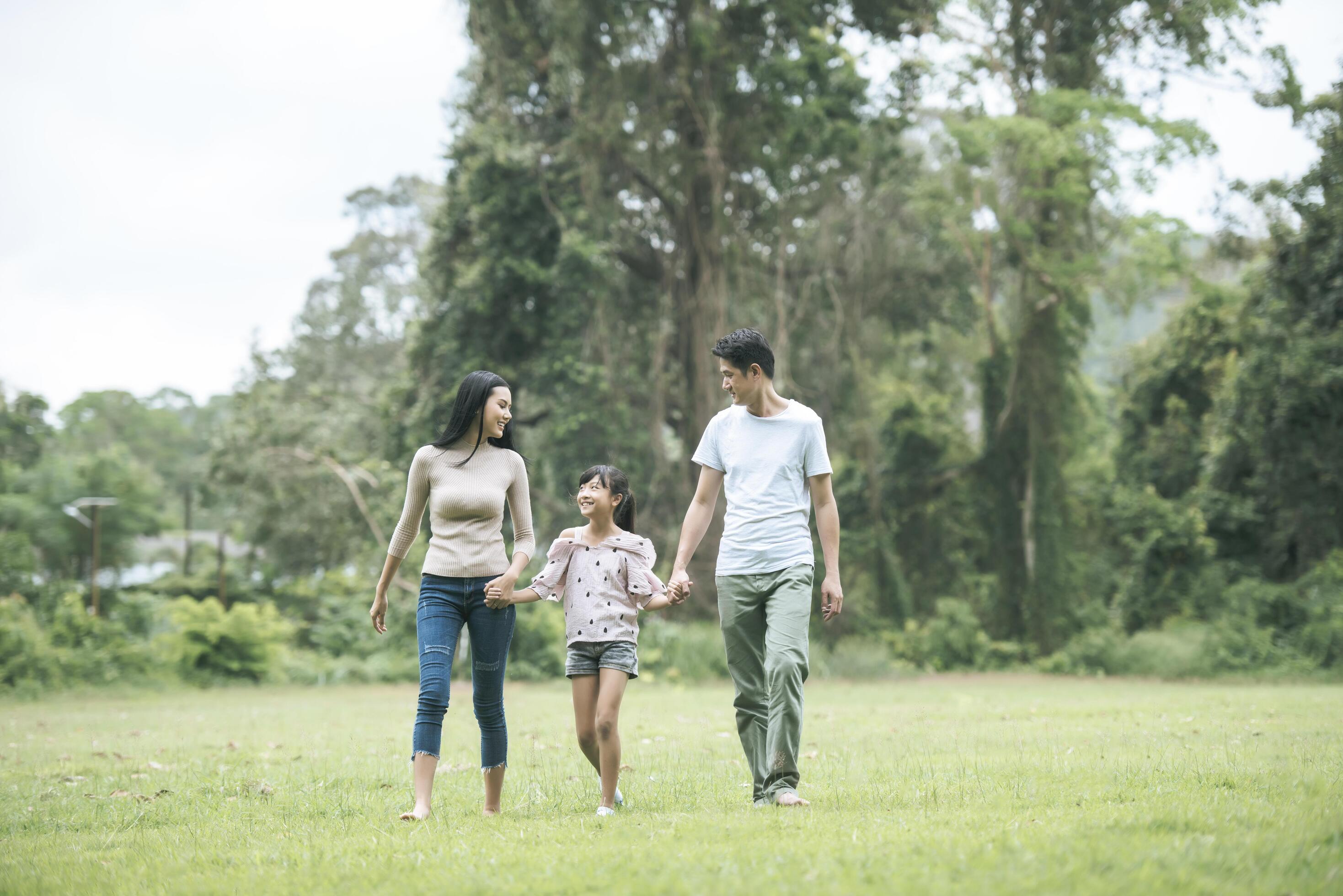 Happy parents and their daughter walking in the park, Happy family concept. Stock Free