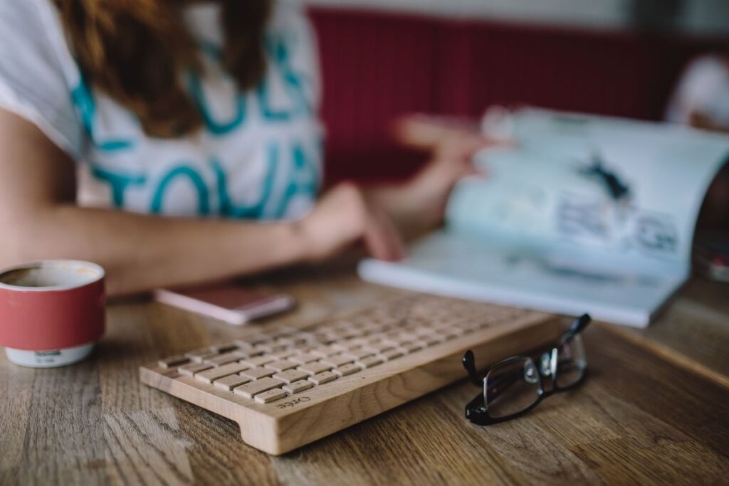 Closeup of female hands typing text on a wireless wooden keyboard Stock Free