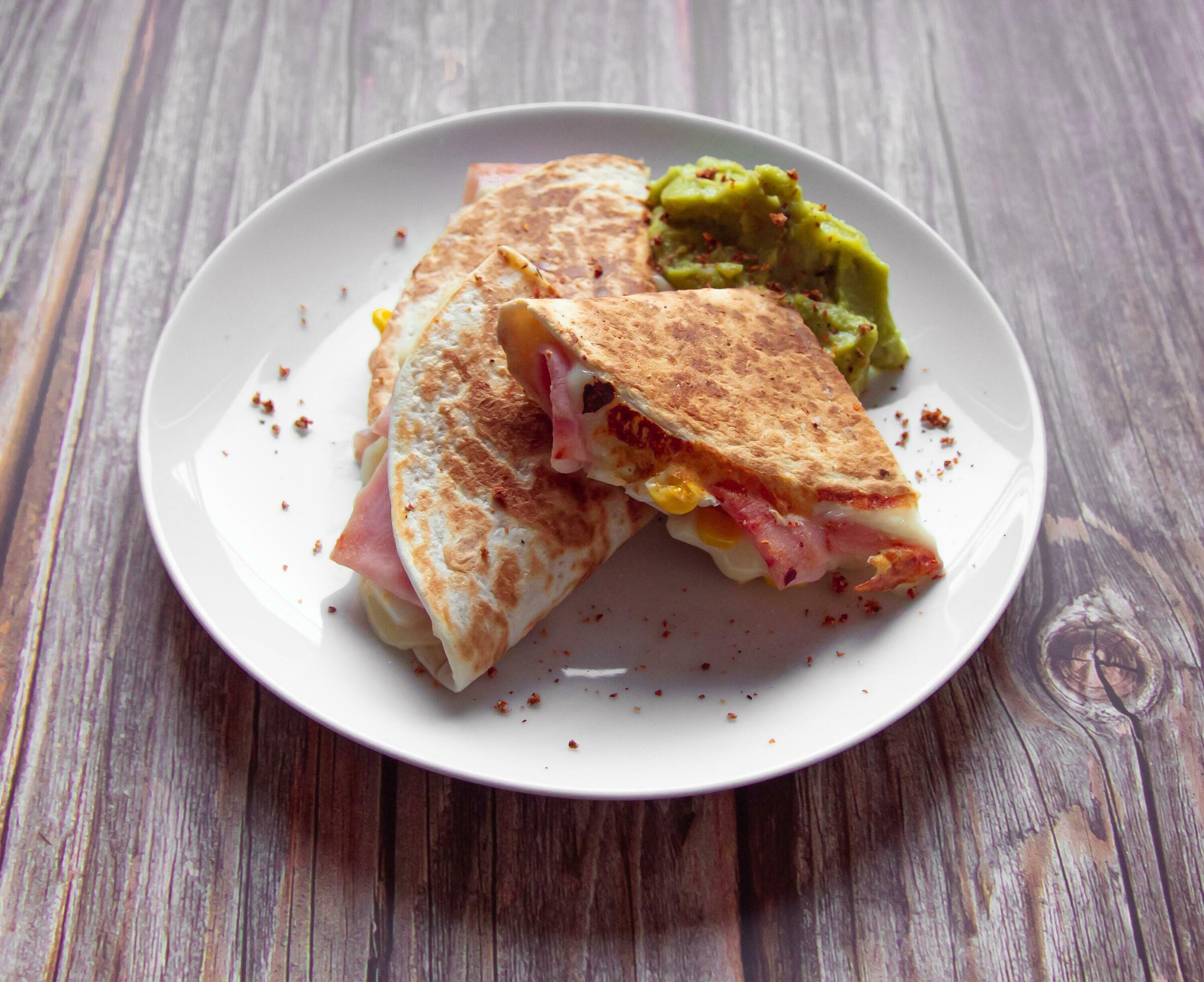 A plate of food with a quesadilla and guacamole on it. Stock Free