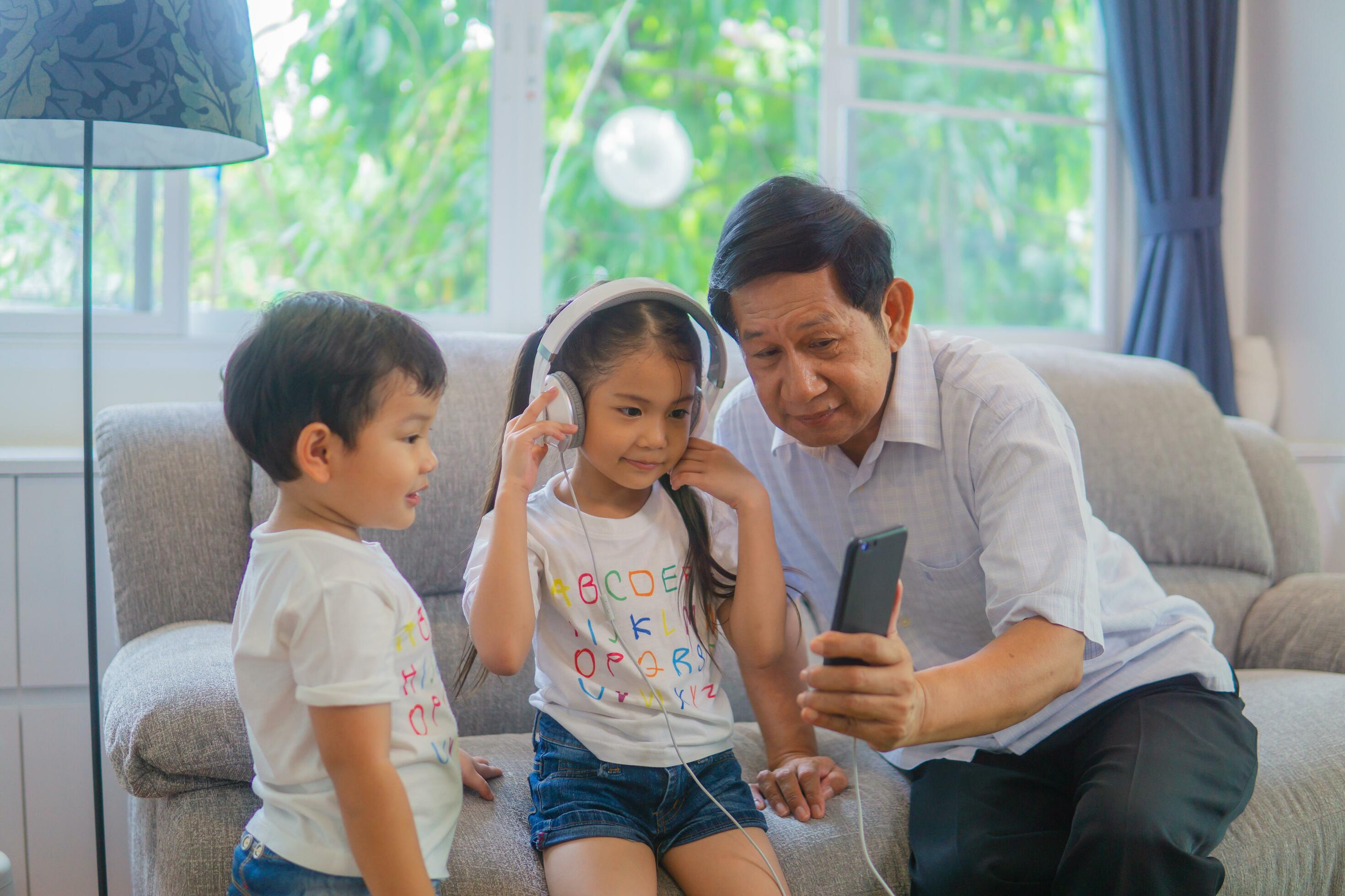 Grandfather and grandson playing video game at sofa. Stock Free