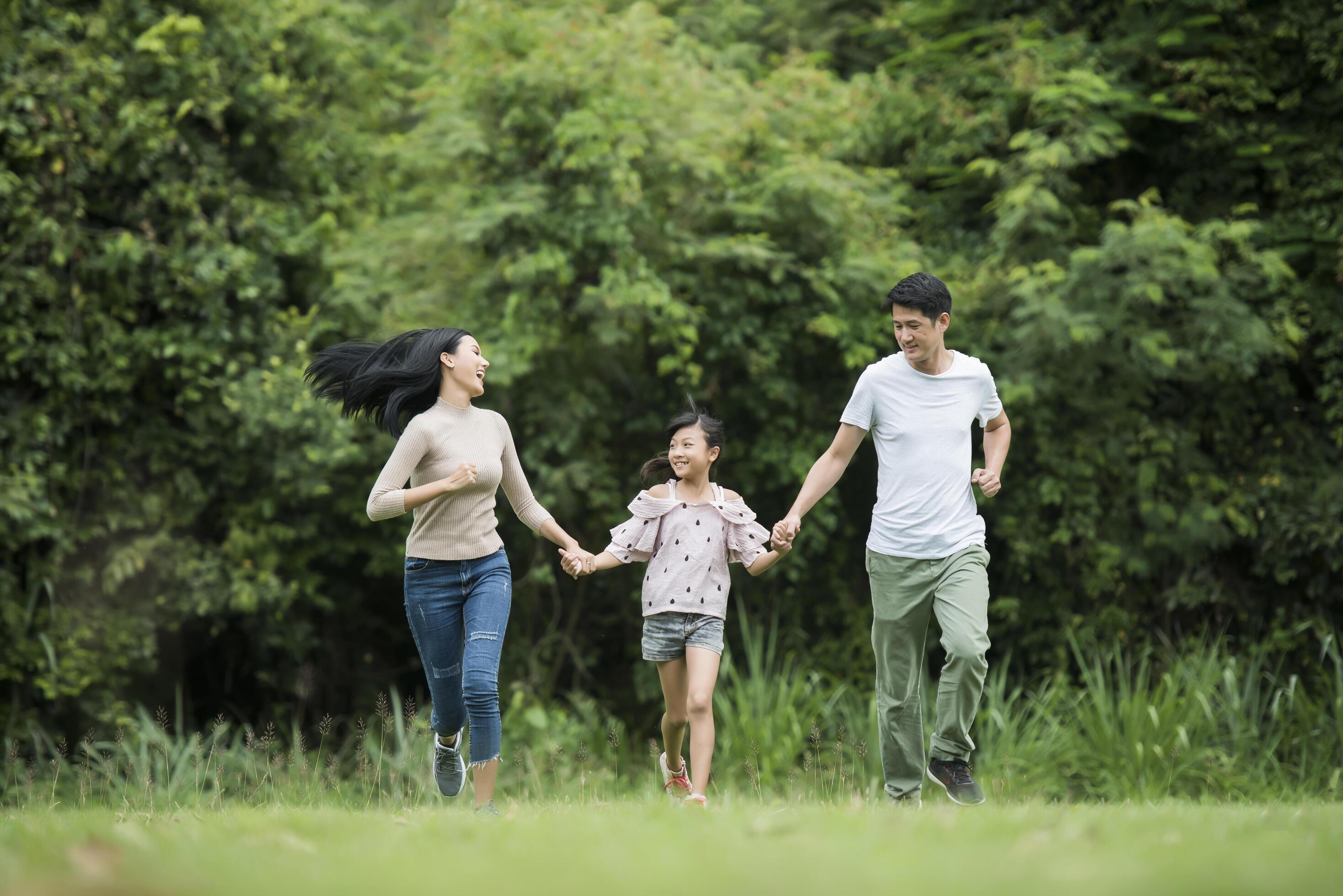 Happy family is having fun Mother, father and daughter are running in park. Stock Free