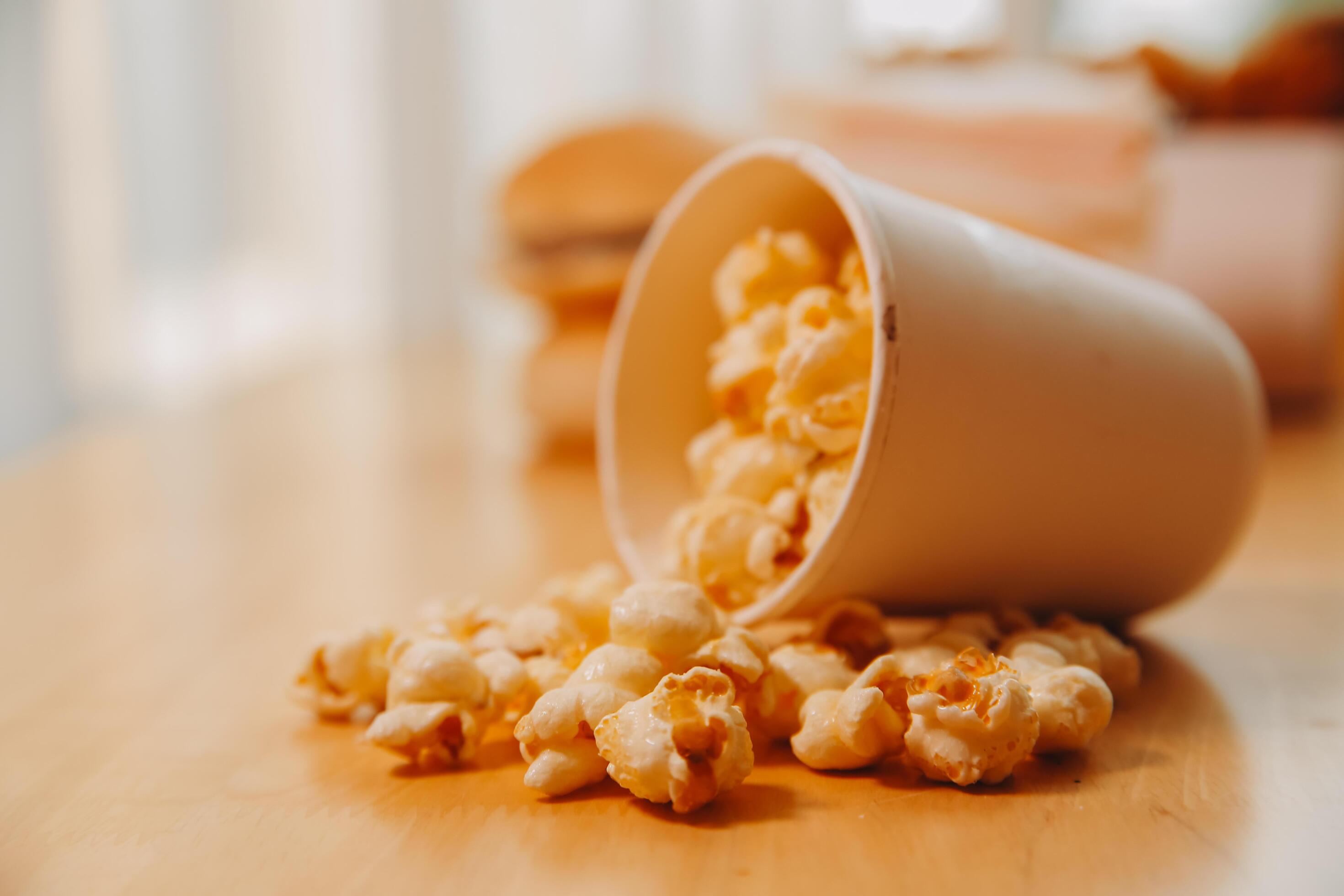 A bucket of popcorn, top-view, warm colors, light brown wooden background, flat lay, daylight macro close-up Stock Free