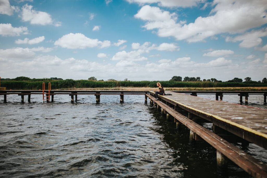 Beautiful blonde woman on a wooden pier by the lake Stock Free