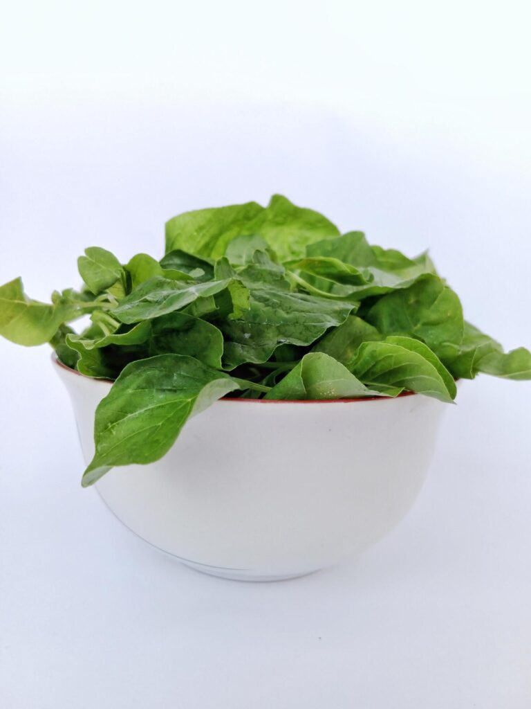 a bowl of spinach on a white background Stock Free