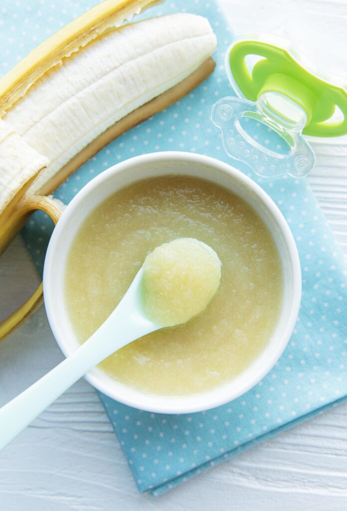 Bowl with fruit baby food and banana Stock Free