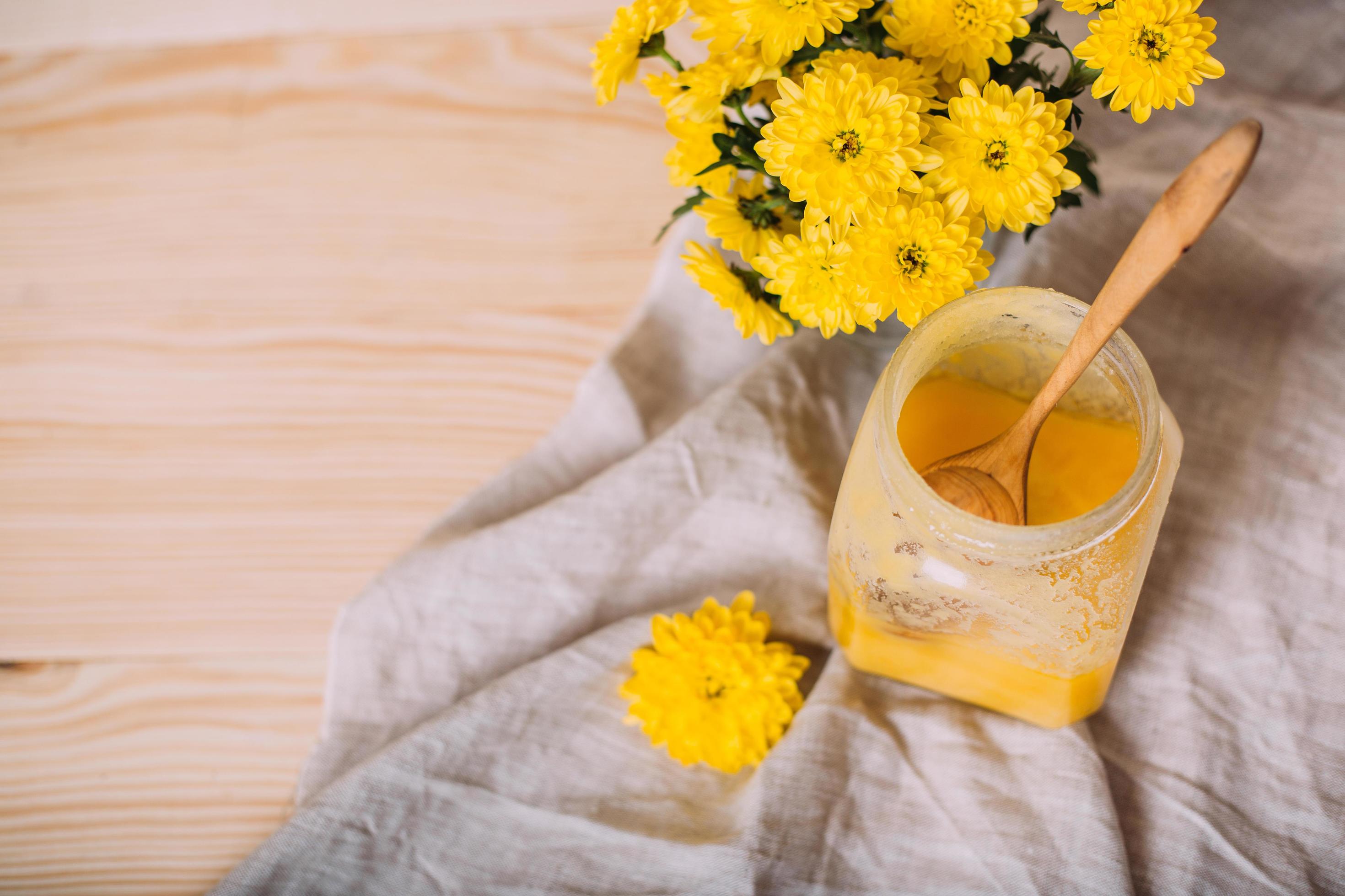 A jar of solid honey and flowers on wooden background. Stock Free