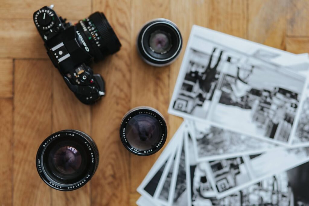 Old Zenit camera and a Canon camera with black-and-white photos on a wooden table Stock Free