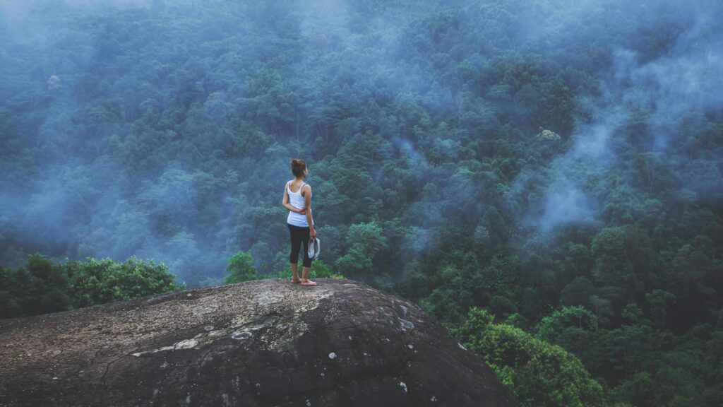 Young woman exercises yoga in the mountains. Asian woman travel nature. Travel relax exercises yoga touch natural fog on mountain peak. Stock Free