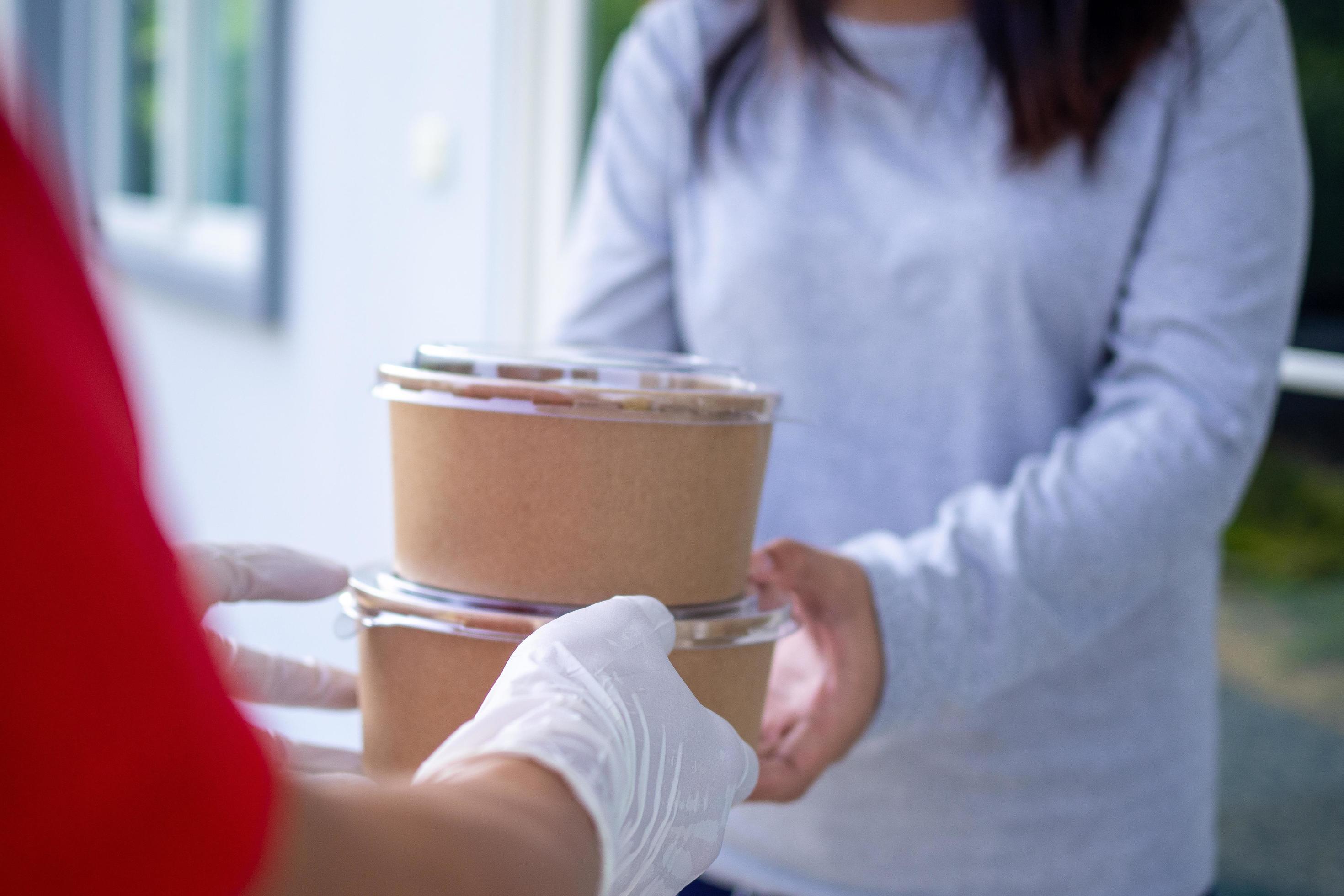 Delivery staff wear gloves for good hygiene, send food boxes to recipients in front of the house. Order food online and fast delivery. Stock Free