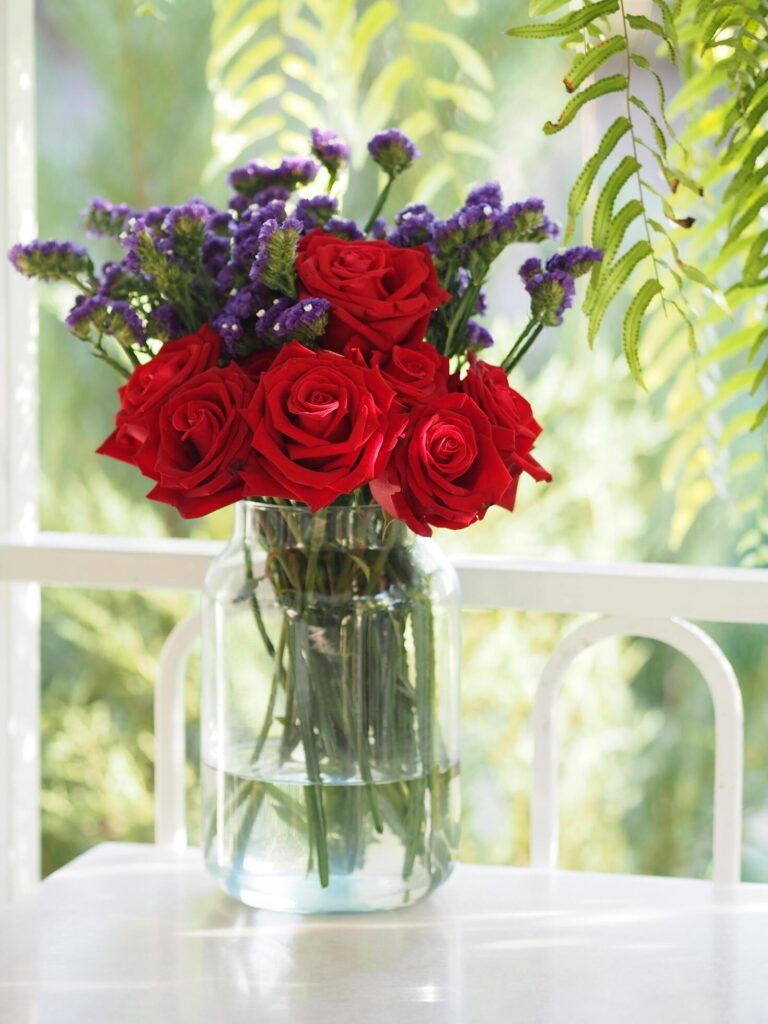 Red rose and Dried statice flower soft pink, violet color in clear glass vase vintage style, Concept for write text design in front background Stock Free