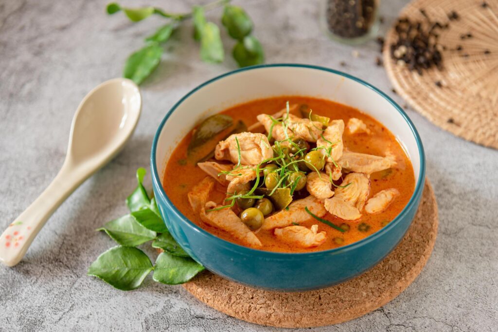 Thai red curry with minced chicken, fresh vegetable and herb in bowl on table, Thai menu and background Stock Free