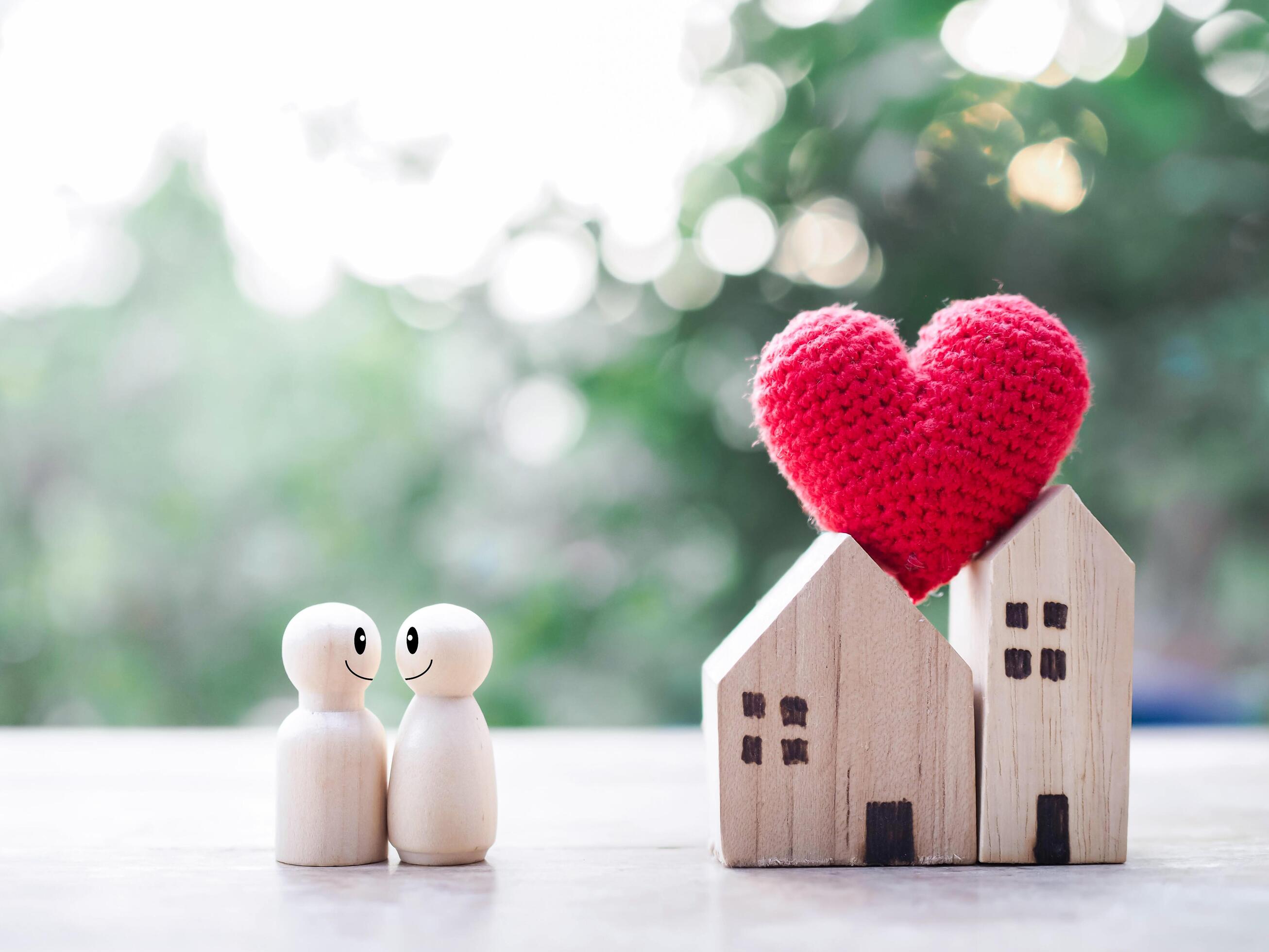 Wooden figure couple happy face and Miniature house with heart. The concept of romantic feelings, family relationship. Stock Free