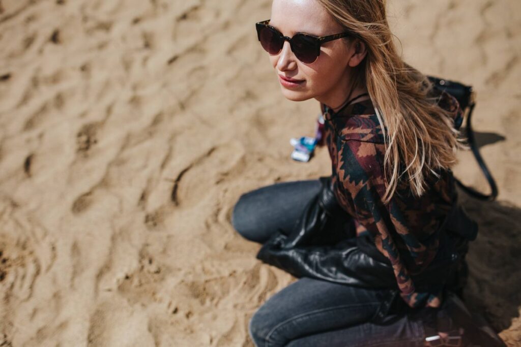 Young woman wearing a leather jacket and sunglasses on the beach Stock Free