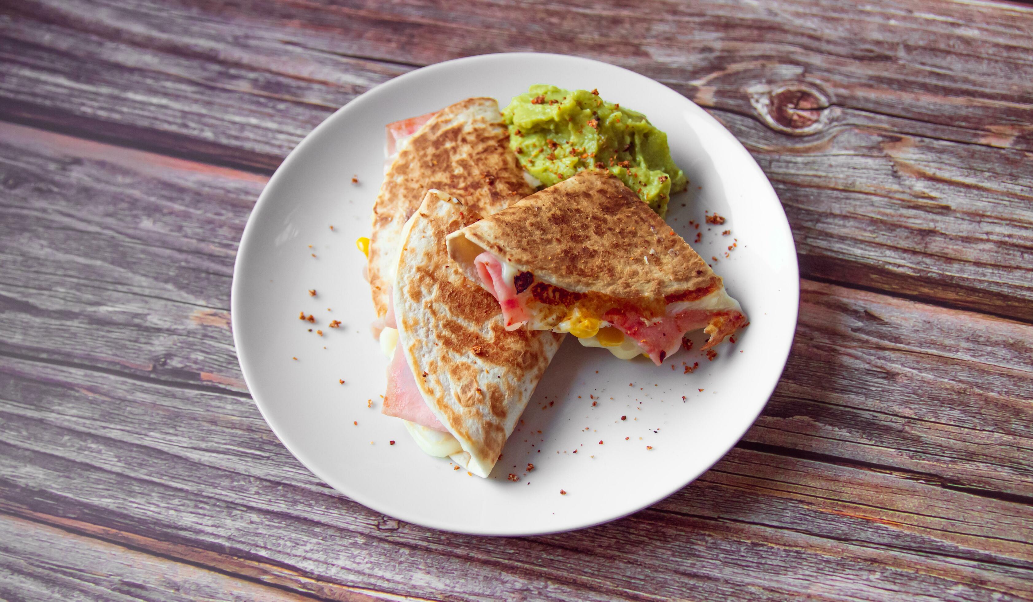 A plate of food with a quesadilla and guacamole on it. Stock Free