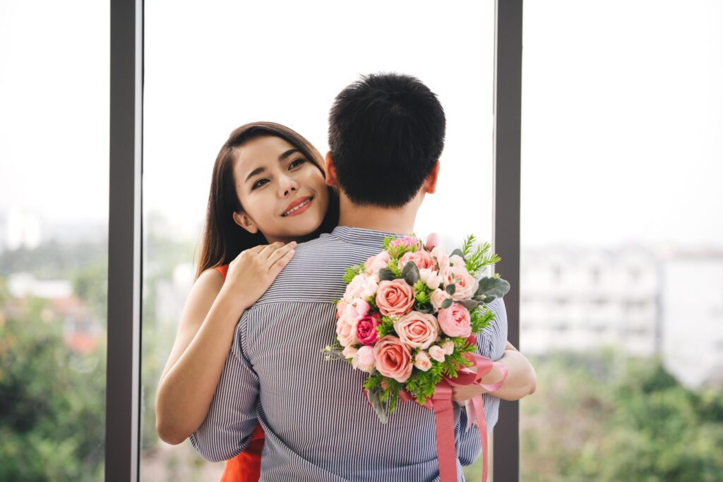 Man couple give gift a romantic flower bouquet it to girlfriend. Woman smile and hug together. Stock Free