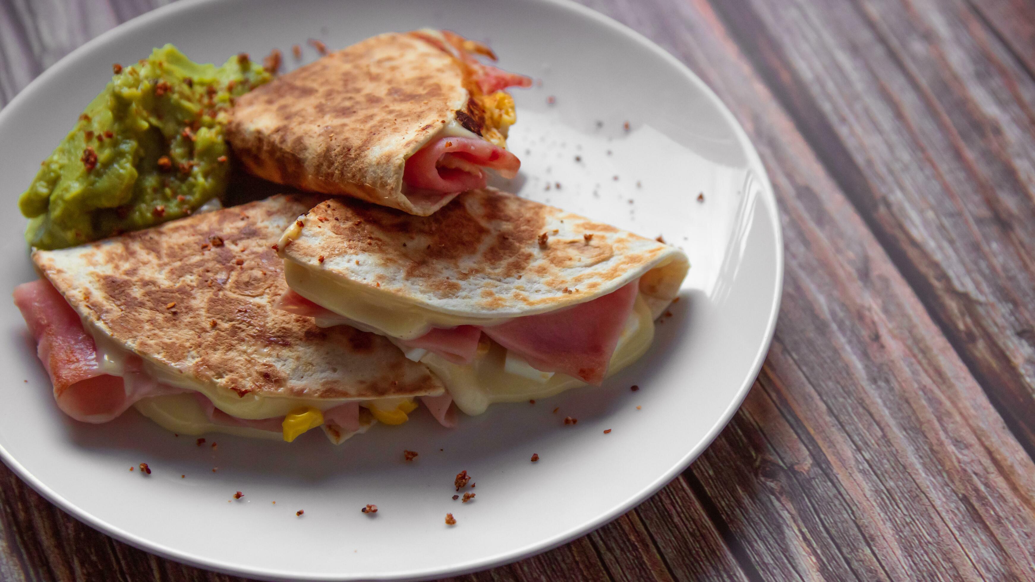 A plate of food with a quesadilla and guacamole on it. Stock Free