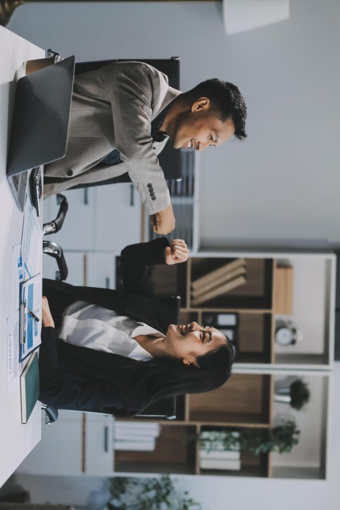 Young asian business woman giving high five with friends while working with computer laptop at office. Stock Free