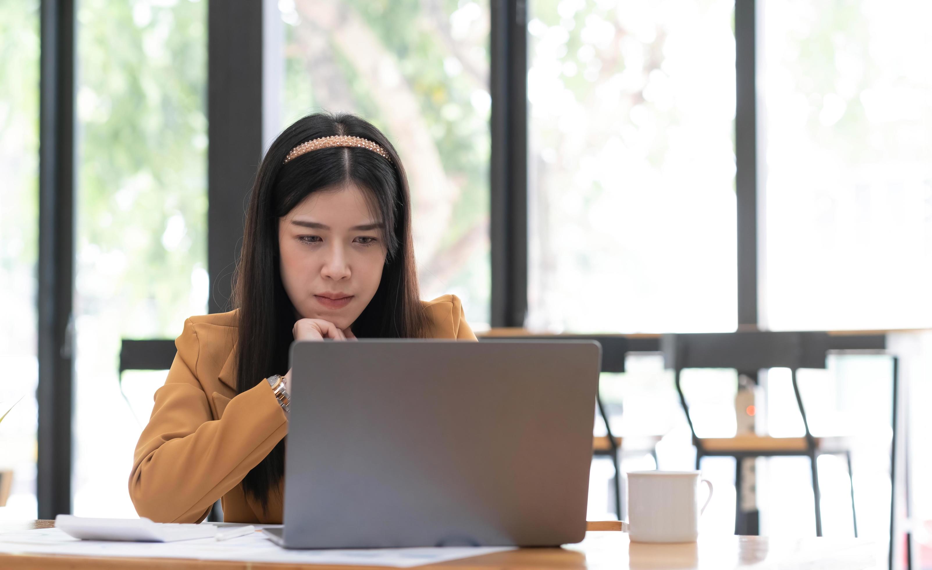 Young Asian woman working at office using a laptop computer on a table. Stock Free