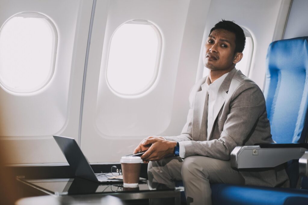 Stressed and professional Asian businessman in a business class, having a serious phone call with someone during the flight to a business meeting. Stock Free