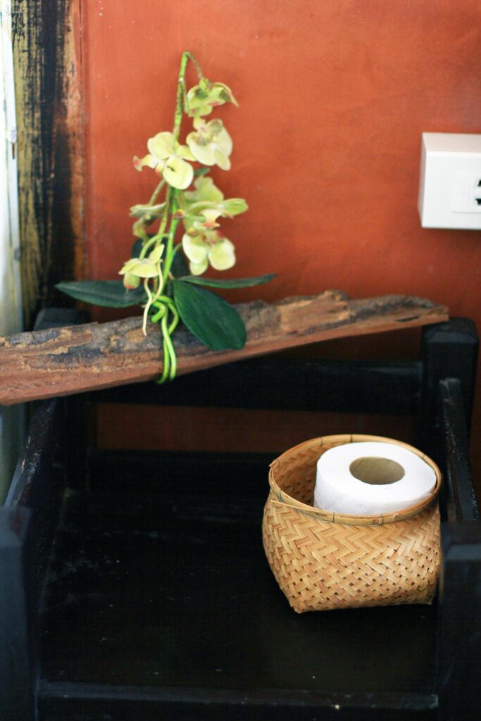 Tissue in a basket and orchid flowers on Wooden shelf hanging on orange wall decoration in bathroom vintage style Stock Free