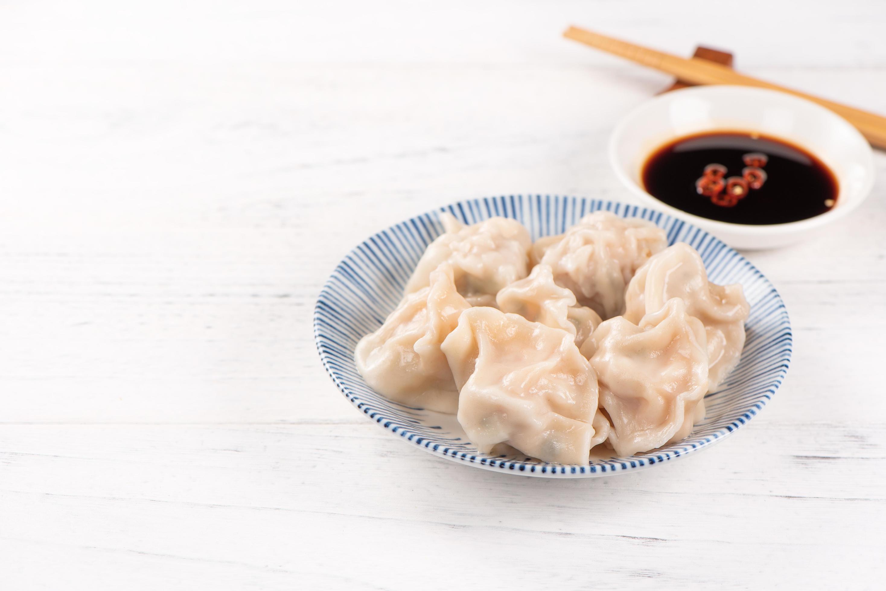 Fresh, delicious boiled pork gyoza dumplings, jiaozi on white background with soy sauce and chopsticks, close up, lifestyle. Homemade design concept. Stock Free