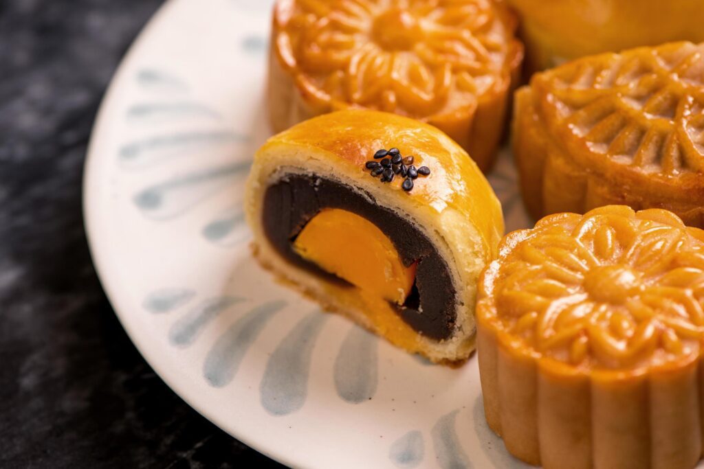 Tasty baked egg yolk pastry moon cake for Mid-Autumn Festival on black slate dark background. Chinese festive food concept, close up, copy space. Stock Free