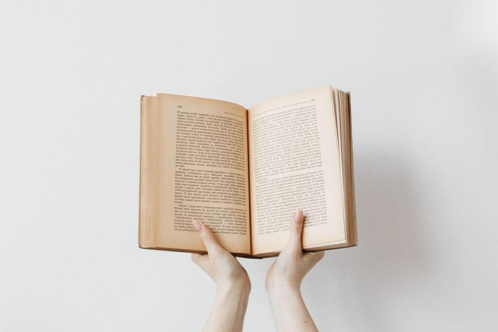 A young woman in a woolly sweater holds books Stock Free