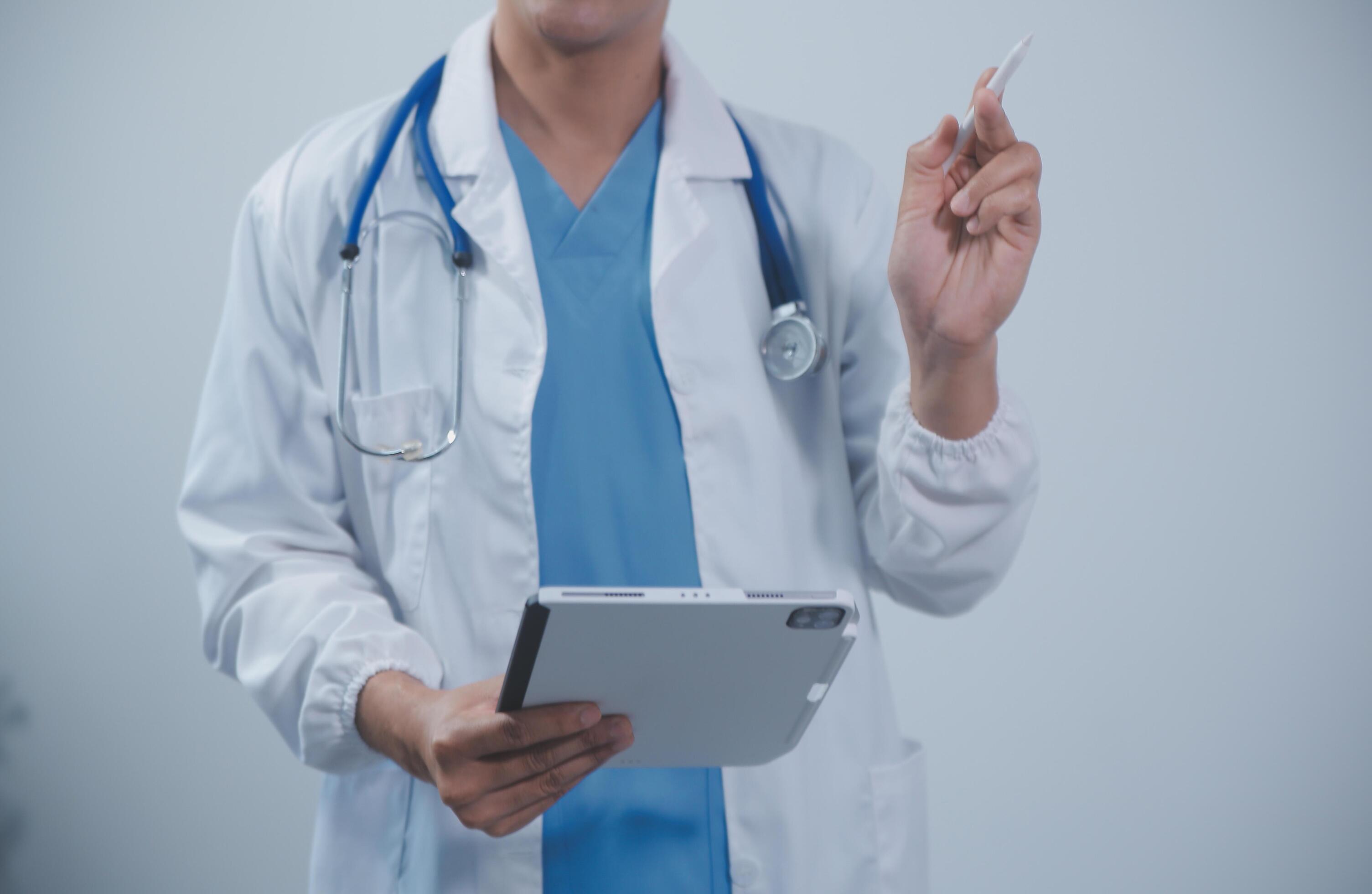 Mature male doctor with tablet pc is giving presentation. Blurred background indoors. Stock Free