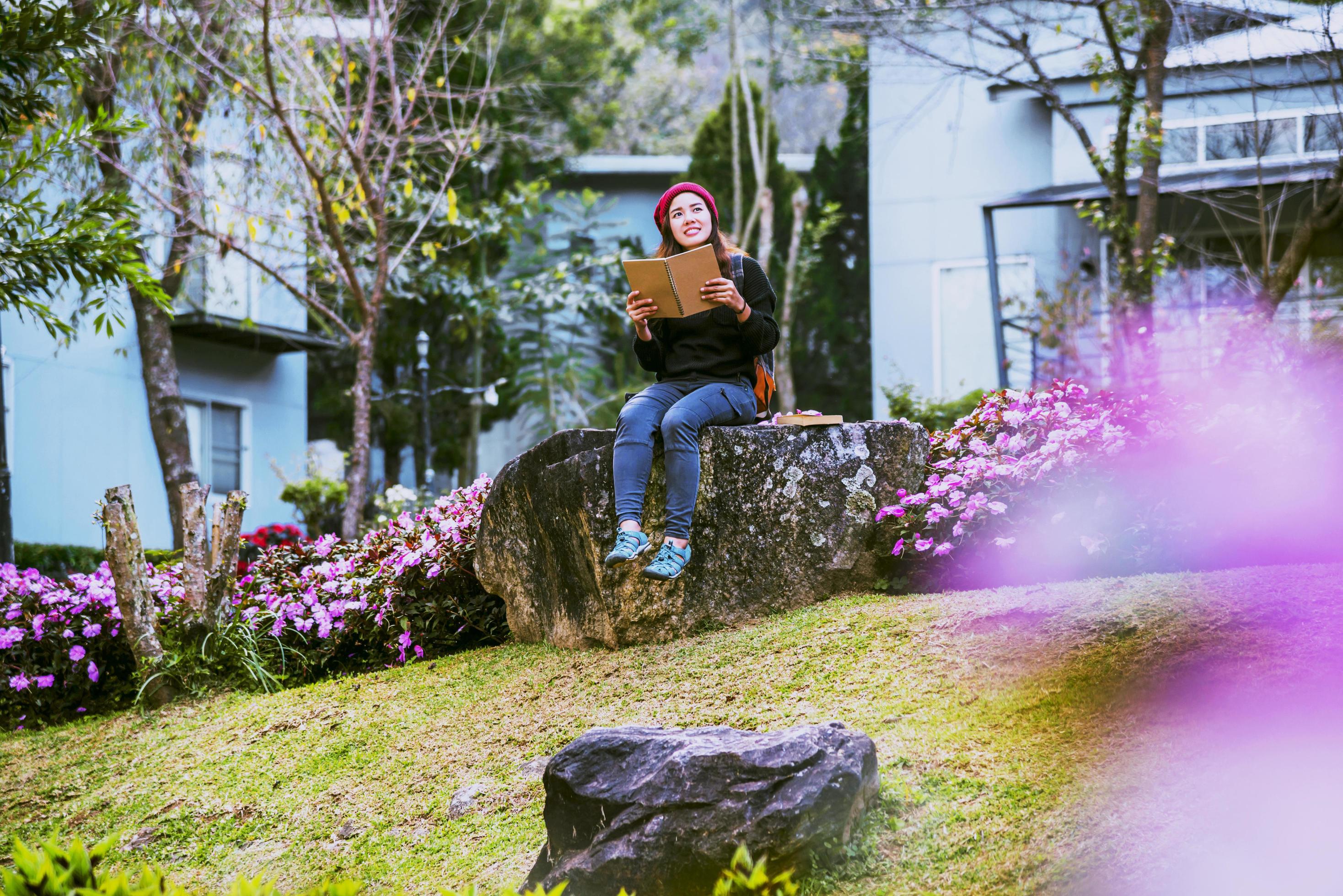 woman travel nature in the flower garden. relax sitting on rocks and reading books In the midst of nature at doi Inthanon. Stock Free