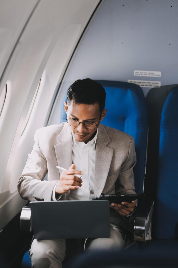 Airplane, travel and portrait of businessman working on laptop computer and smartphone while sitting in airplane. Stock Free