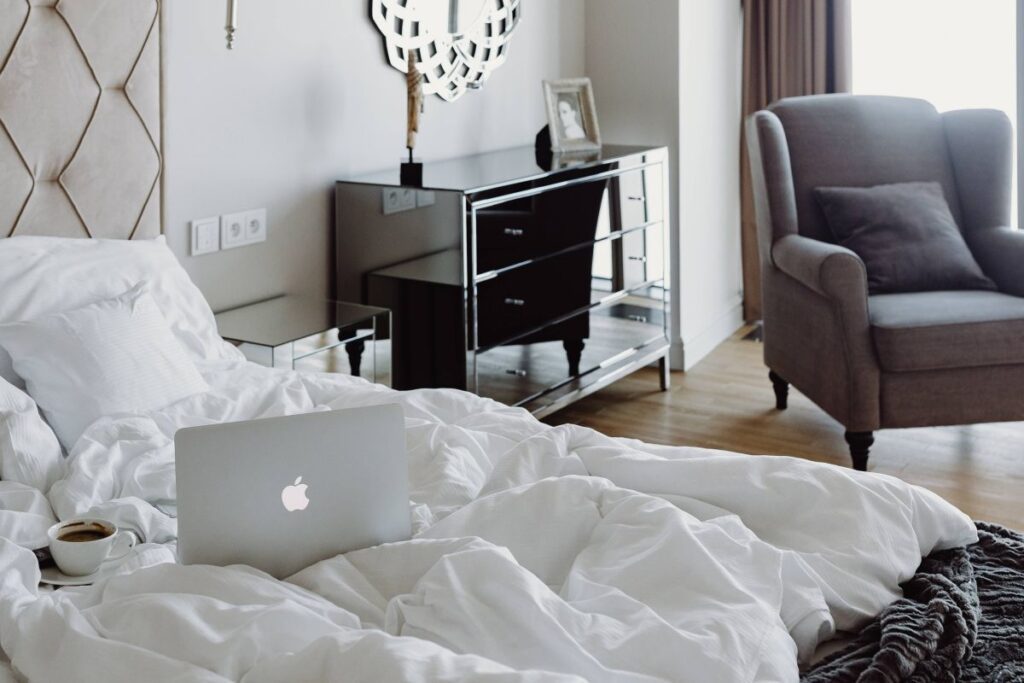 Woman working on a laptop while enjoying a breakfast coffee and chocolate in bed Stock Free