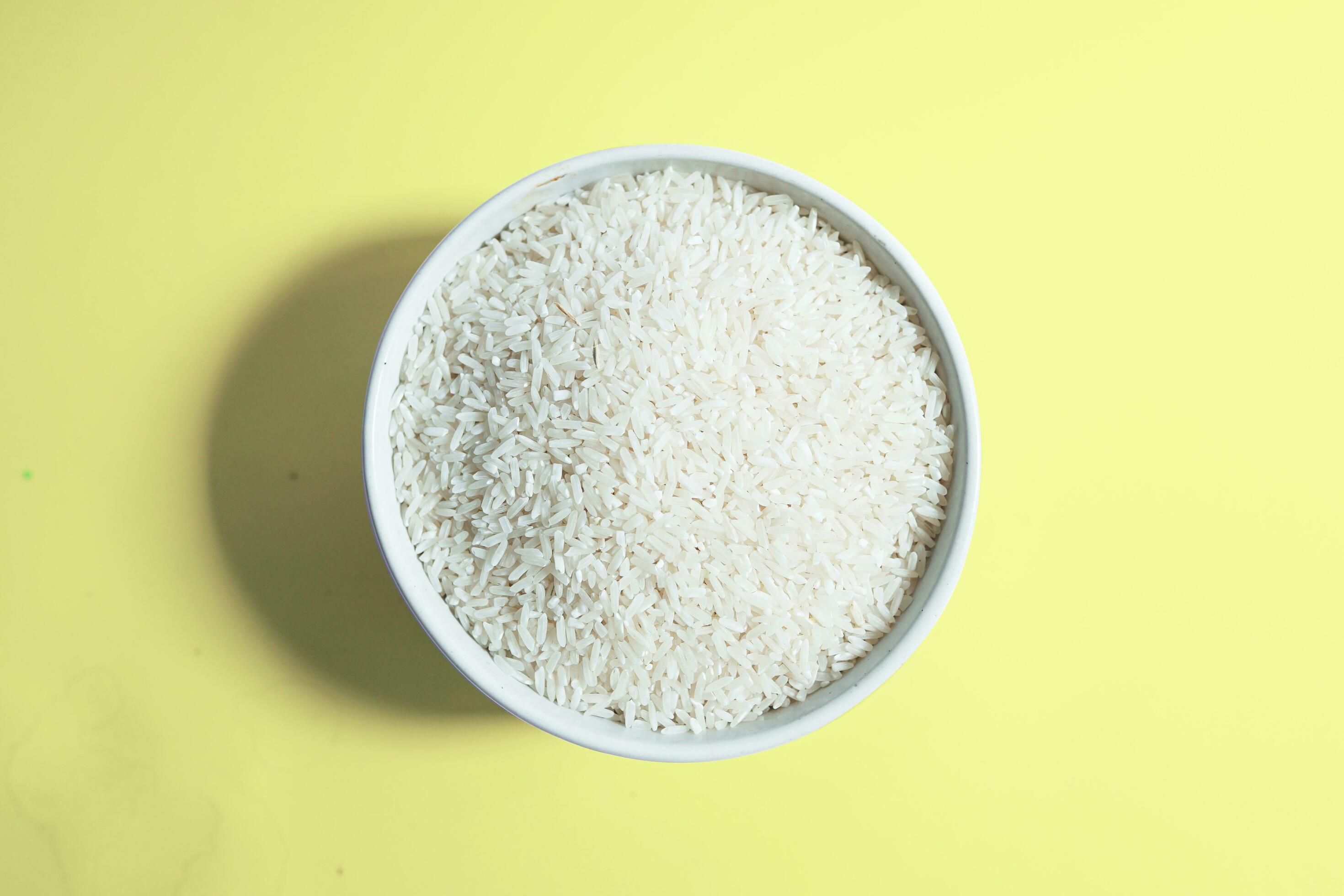 Healthy food. White ceramic bowl with high carb rice on yellow background. Top view, high resolution product. Stock Free