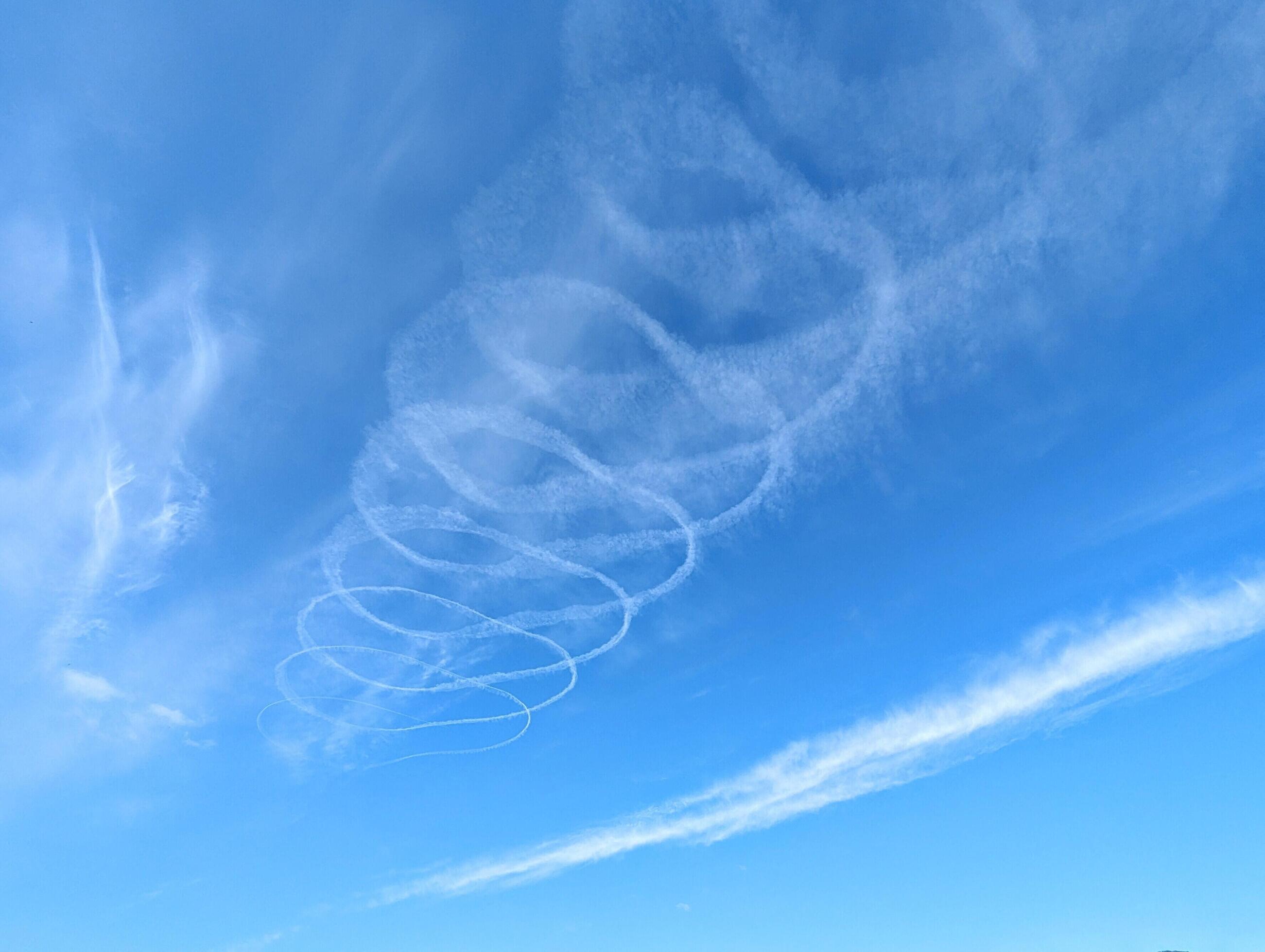 Blue sky with chemtrails from air plane, contrails, nature background, spiral shaped clouds Stock Free