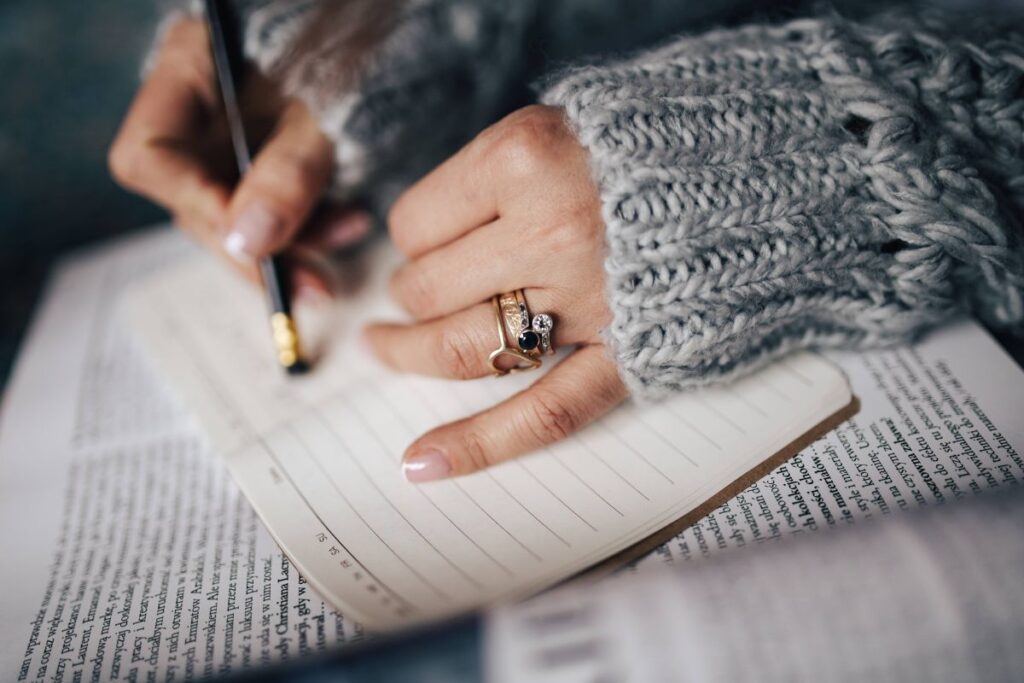 
									Woman in a grey sweater taking notes in an organizer Stock Free