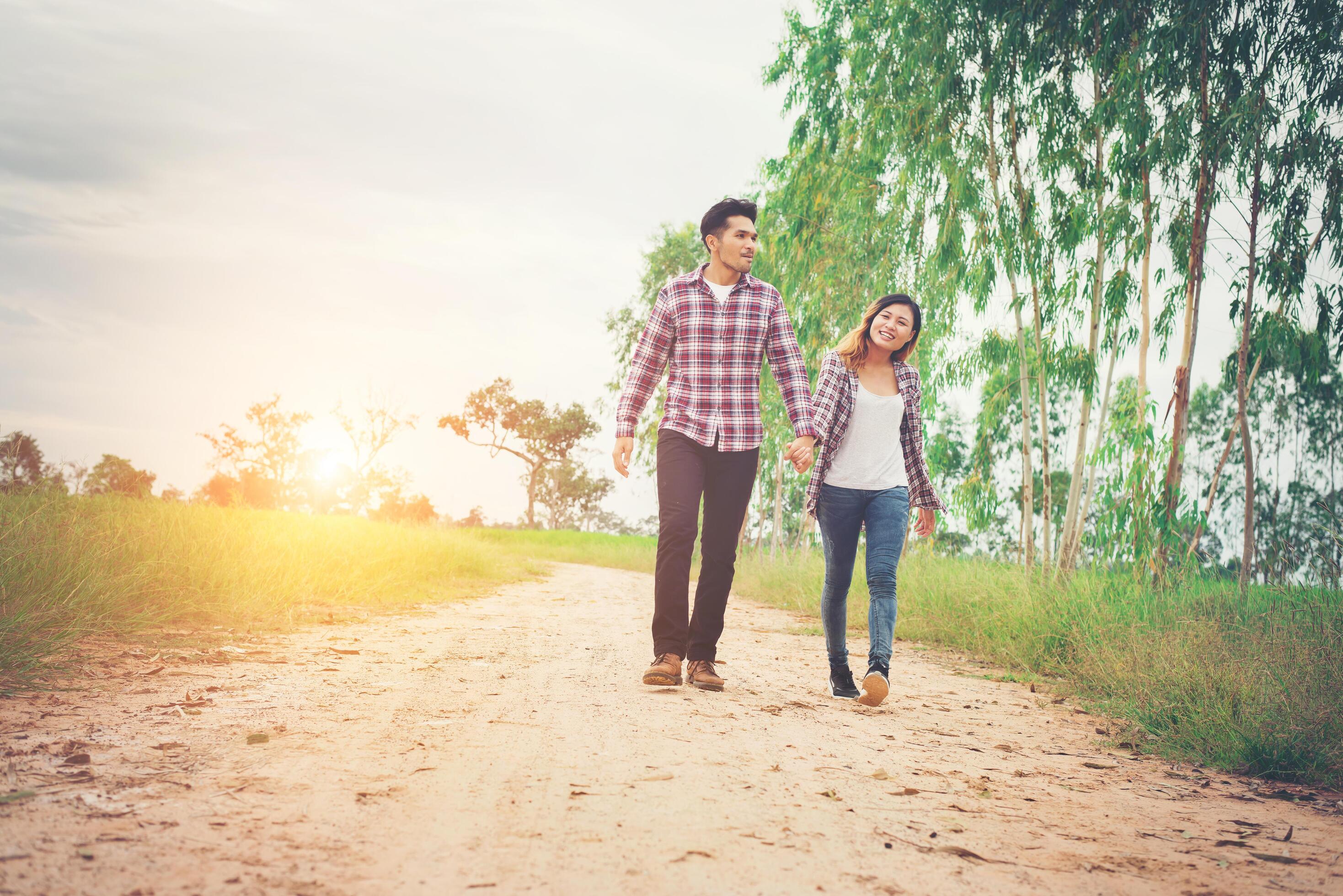 Young hipster couple walking on rural road enjoying with nature, Love couple,holiday traveling, spend time together. Stock Free