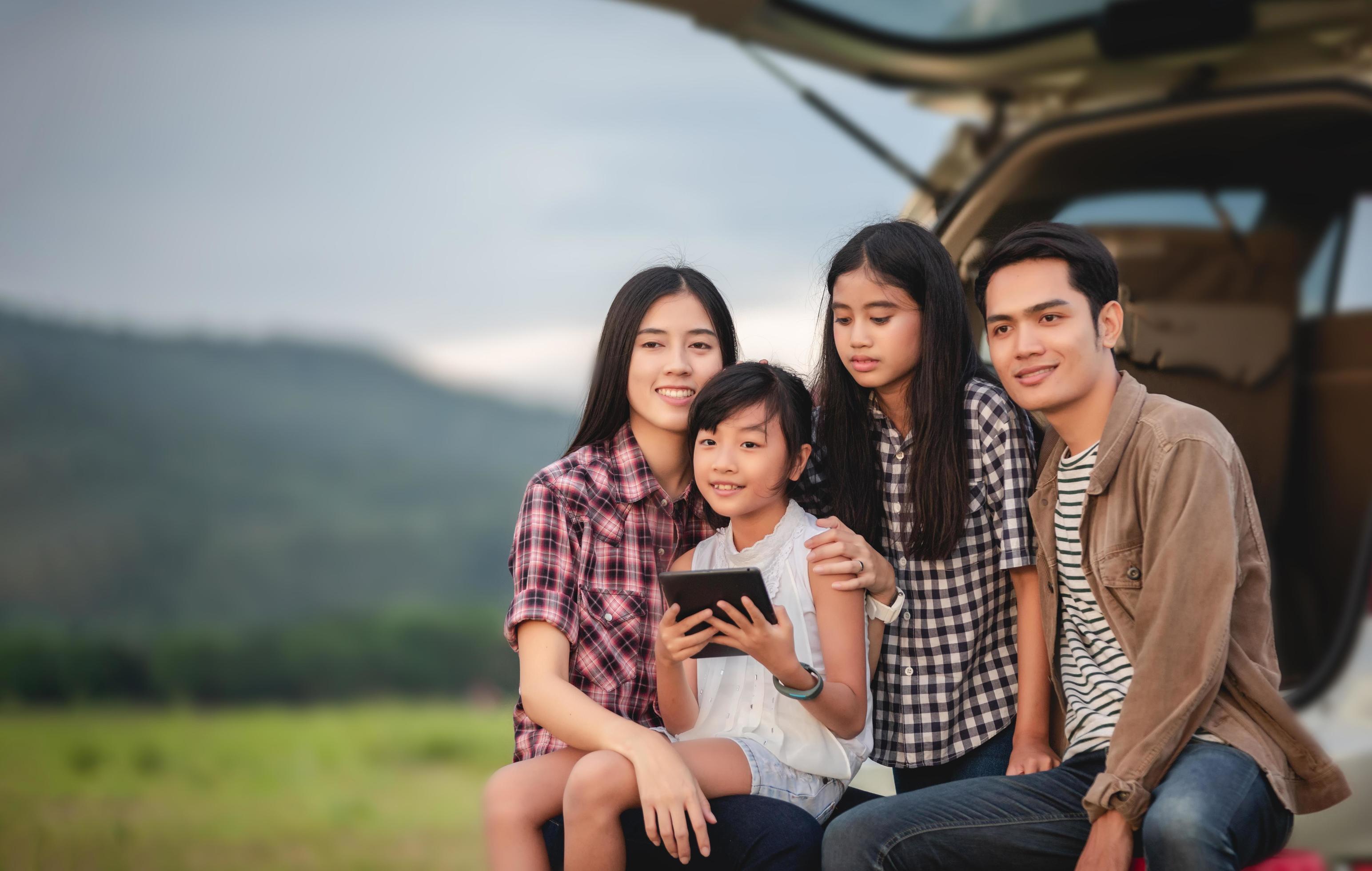 Happy little girl with asian family sitting in the car for enjoying road trip and summer vacation in camper van Stock Free