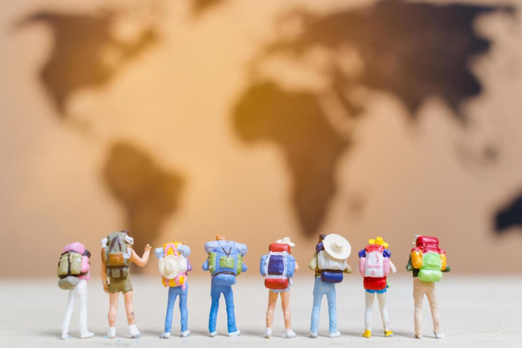 Miniature travelers walking on a world map, traveling and exploring the world concept Stock Free