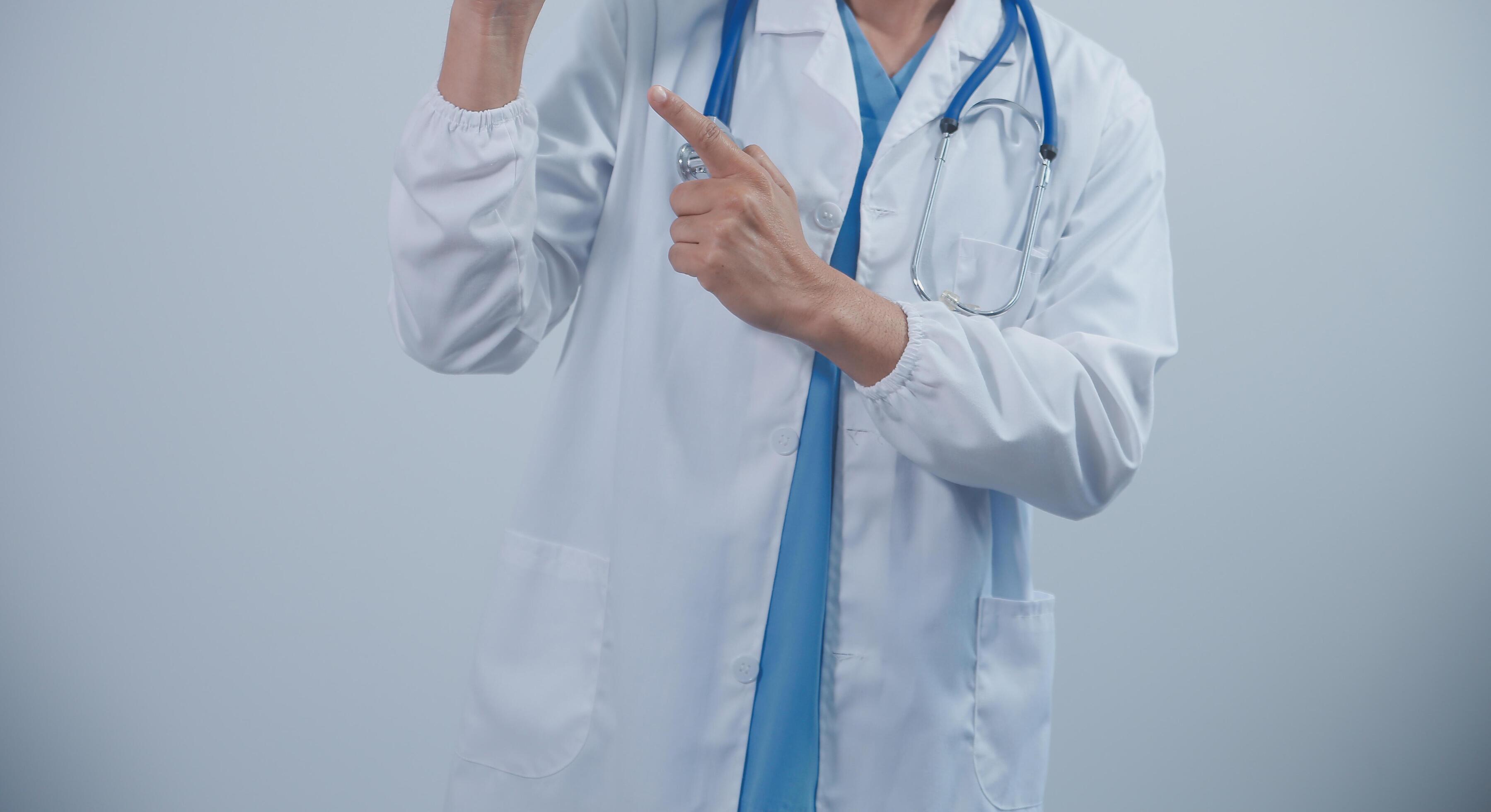 Mature male doctor with tablet pc is giving presentation. Blurred background indoors. Stock Free