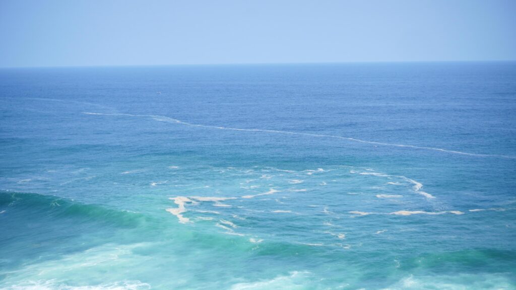 Front view over the ocean and white foam waves. Feel calm, cool, relaxed. Idea for cool background and copy space above. Stock Free