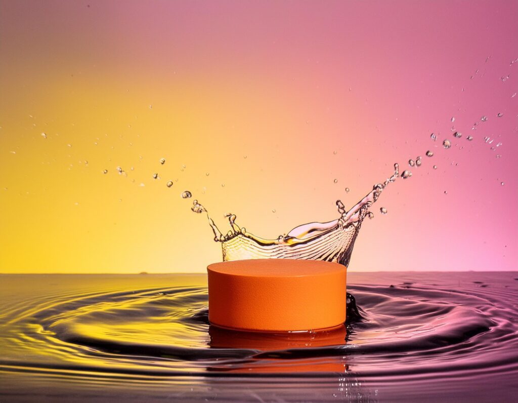 empty orange podium mockup with water splash on a gradient background for product display Stock Free