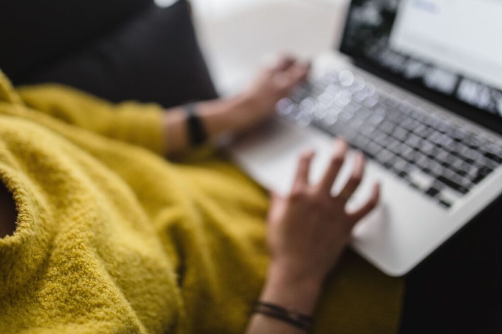 Young woman sitting on the sofa and working on her laptop Stock Free