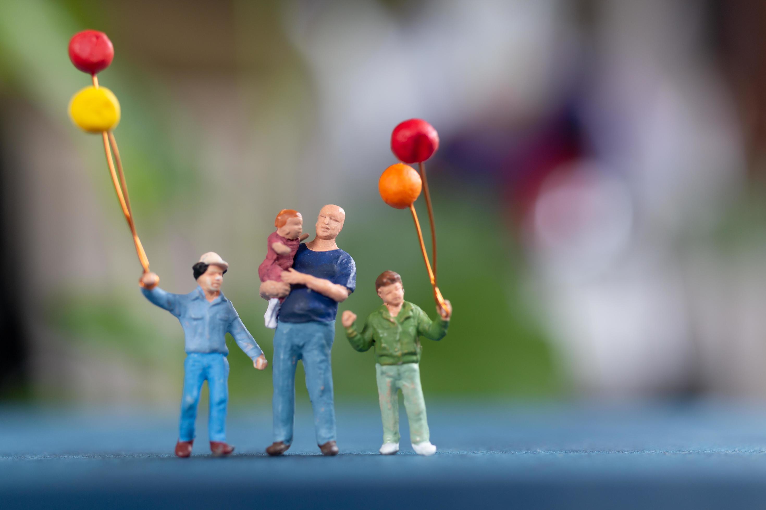 Miniature family holding balloons in the park, World Children’s Day concept Stock Free