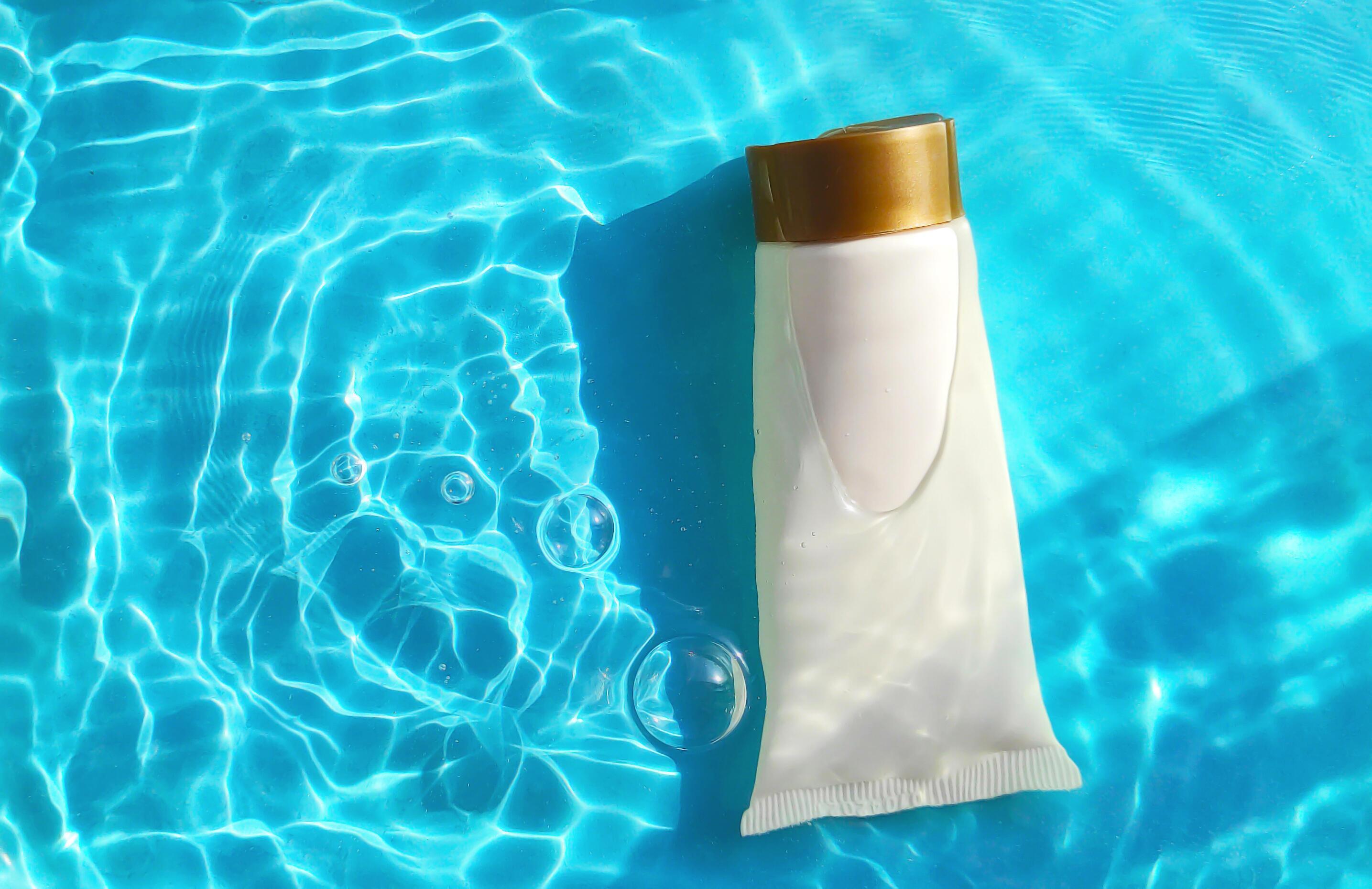 Mock up tube with cosmetic product for moisturizing in water on blue background. Template for design Stock Free