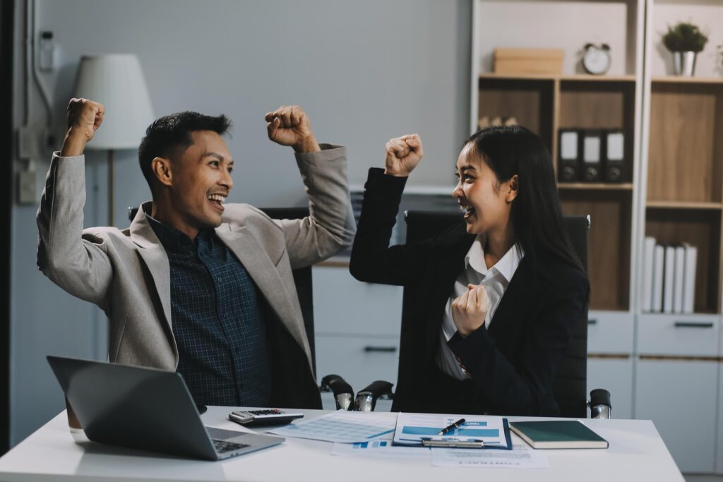 Young asian business woman giving high five with friends while working with computer laptop at office. Stock Free