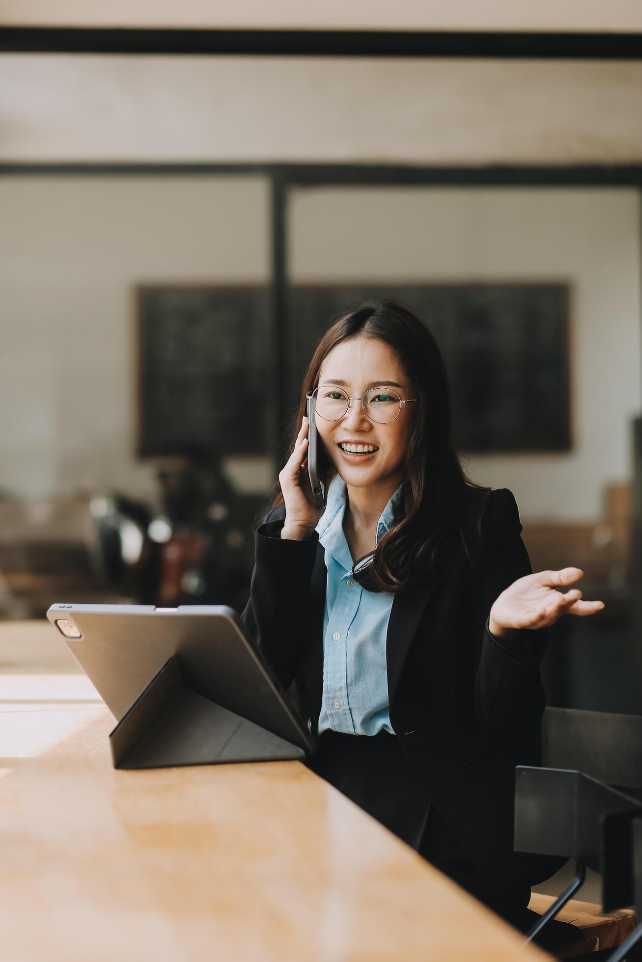 Asian woman entrepreneur busy with her work in the office. Young Asian woman talking over phone or cellphone while sitting at her desk. Stock Free